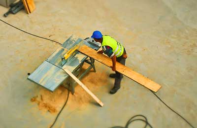 worker operating wood working machine at a construction site