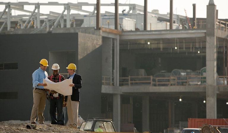 superintendent competent person developer reviewing a blueprint of a new construction building